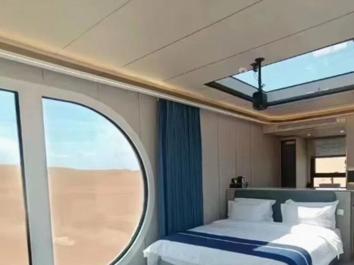 Manufacturer-supplied photograph of a compact cabin interior with a bed, glazing, and overhead window